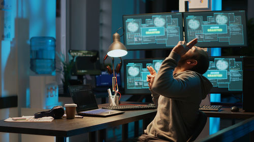 Rear view of man using laptop at office