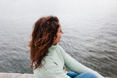 Young beautiful woman sitting by the river at sunset enjoying porto views. travel concept