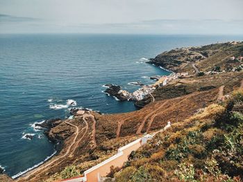 Scenic view of sea by mountains against sky