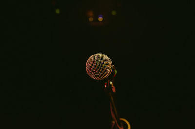 Low angle view of illuminated lighting equipment against black background