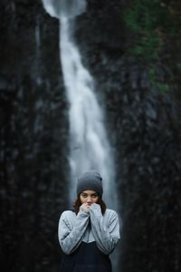 Portrait of woman standing against waterfall