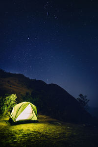 Illuminated tent on field against sky at night