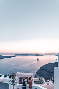 People by sea against sky during sunset