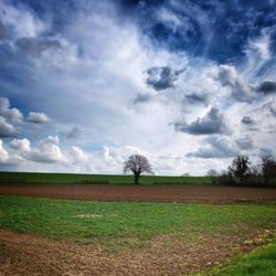 Scenic view of field against cloudy sky