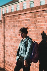 Full length of woman looking at brick wall