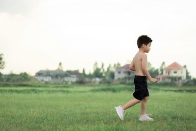 Side view of shirtless boy on field