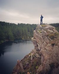 Man standing on rock against sky