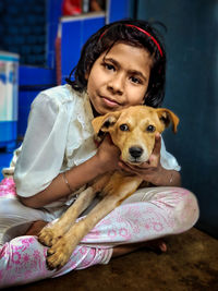 Portrait of girl with dog sitting at home