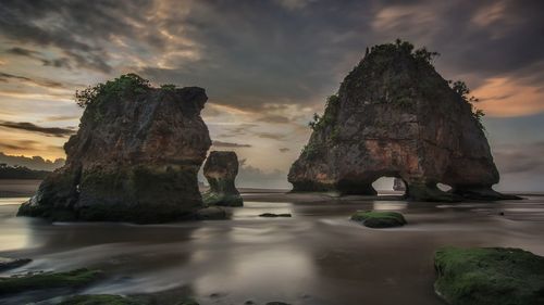 Rock formations in sea against sky during sunset