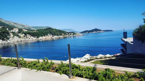 Scenic view of sea by town against clear blue sky