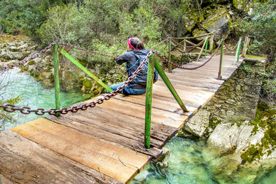 Rear view of man on footbridge over river