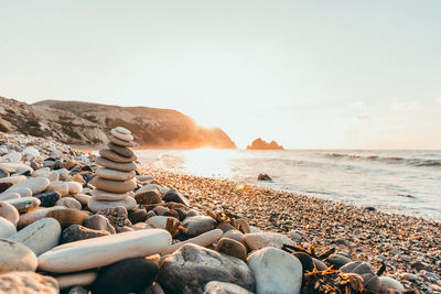 Rocks on beach against sky during sunset