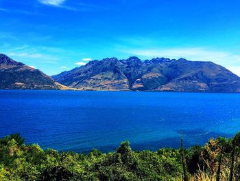 Scenic view of lake and mountains against blue sky