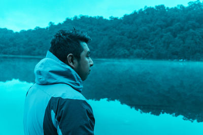 Side view of young man looking at lake