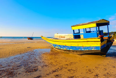 Fishing boat on beach against sky