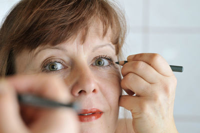 Close-up portrait of woman applying make-up at home