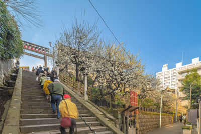 People walking on footpath by footbridge in city