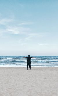 Rear view of man on beach against sky