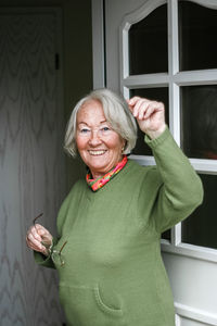 Portrait of senior woman standing against window