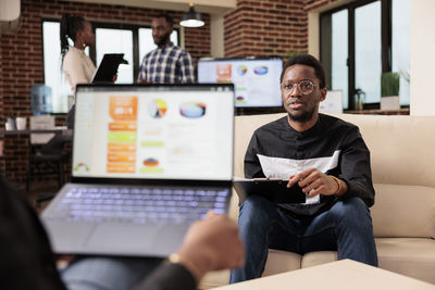 Portrait of young man using laptop while sitting in cafe