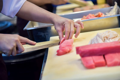 Midsection of chef cutting meat in commercial kitchen