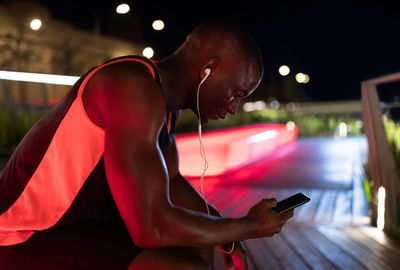 Black runner using smartphone on bench