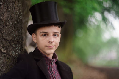 Portrait of young man standing against trees