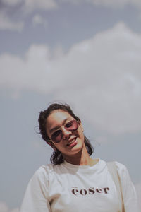 Portrait of smiling woman standing against sky