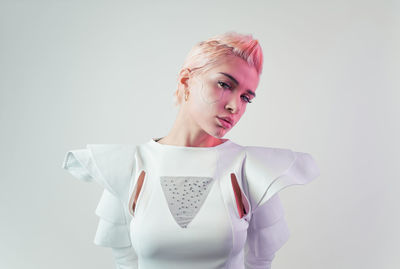 Portrait of young woman standing against white background