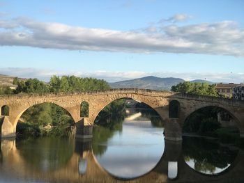 Arch bridge over river against sky