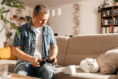 Side view of young man using mobile phone at home