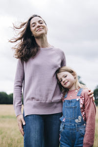 Smiling girl standing with woman at meadow