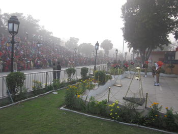 People on fountain in park against sky