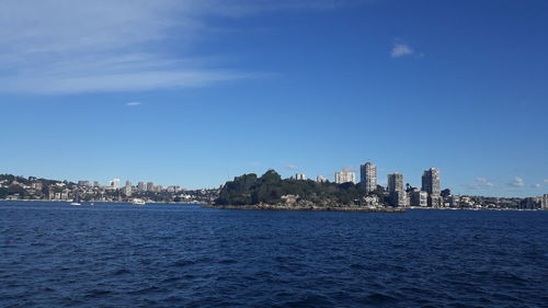 City at waterfront against blue sky