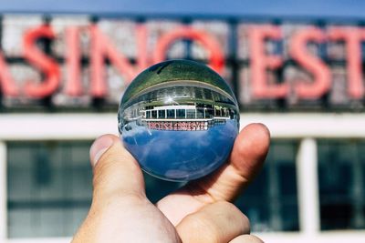 Close-up of hand holding crystal ball with reflection