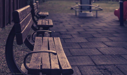Empty wooden benches on footpath in city
