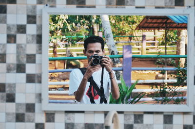 Reflection of man photographing in mirror