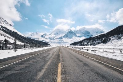 Empty road against snowcapped mountains