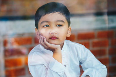 Close-up of thoughtful boy looking away seen through window