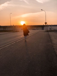 Rear view of man on street at sunset