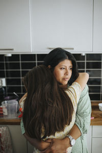 Loving mother hugging daughter at home