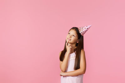 Portrait of young woman wearing hat against pink background