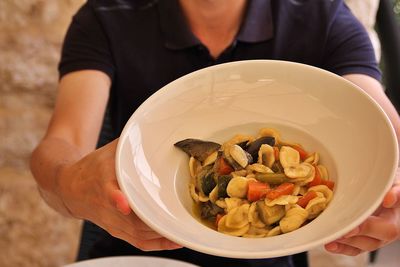 Orecchiette pasta with vegetables, thickly chopped vegetables, man holding a plate of pasta