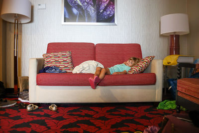 Little girl on couch looking at camera in messy hotel room