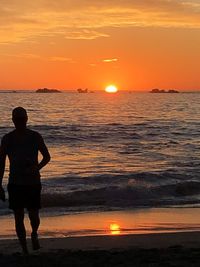 Full length of man standing on beach during sunset