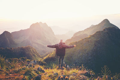 Rear view of man standing on mountain against sky