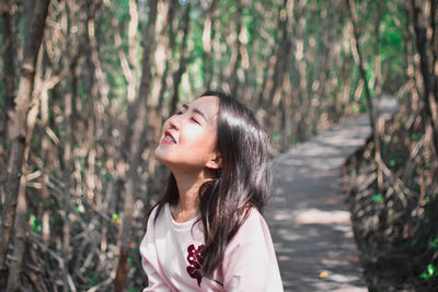 Beautiful woman with eyes closed standing in forest