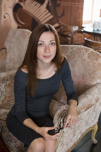 Portrait of smiling young woman sitting on armchair