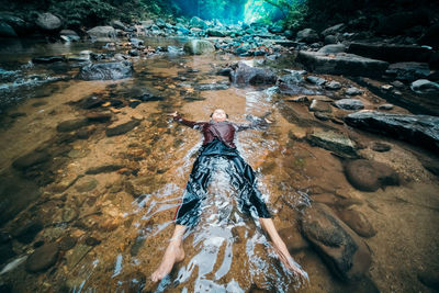 High angle view of boy lying in stream