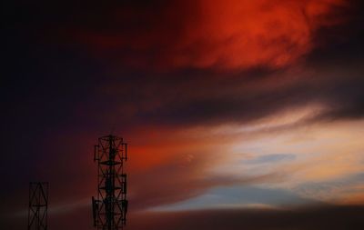 Low angle view of silhouette communications tower against dramatic sky